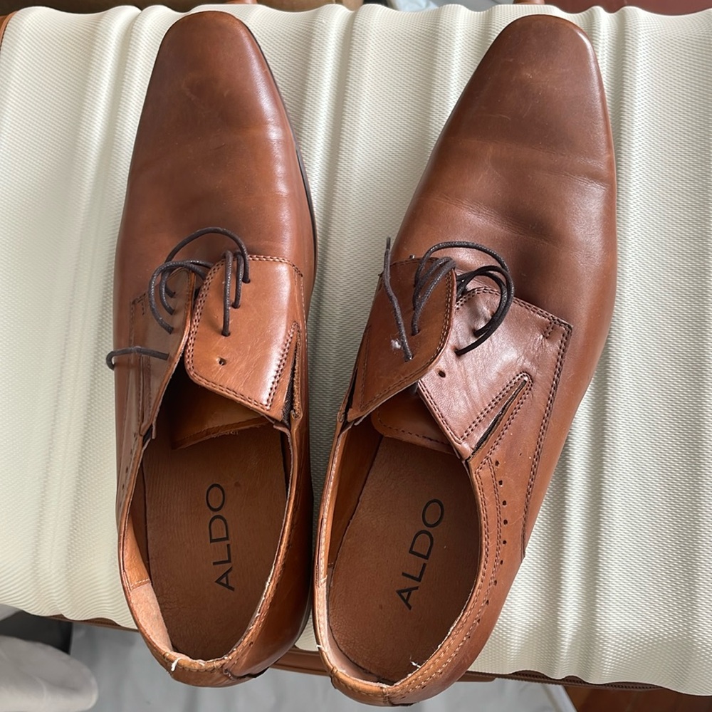 These are shoes from the Aldo brand. They look new with some tiny light marks.